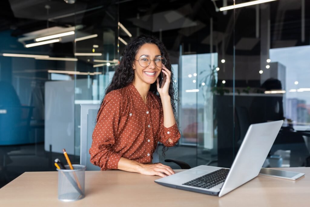 Portrait of successful latin american business woman, office worker smiling and talking on phone